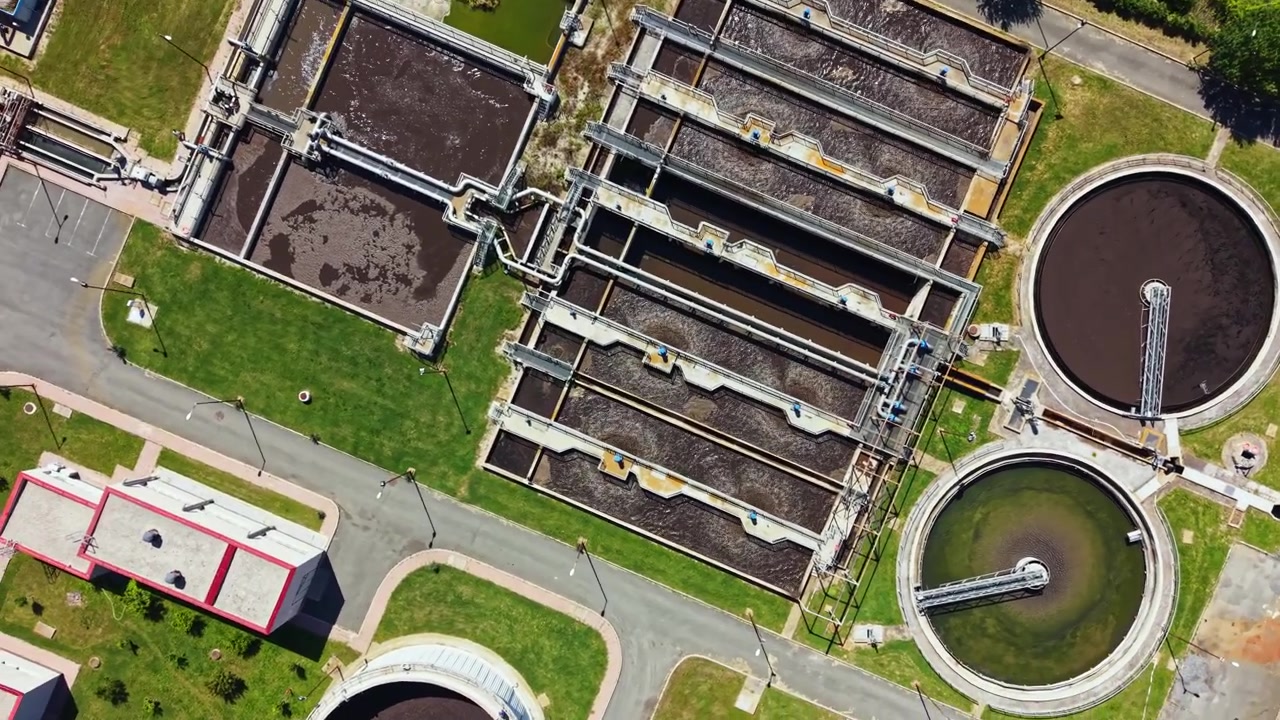 Water treatment facility showing multiple tanks and processing areas in a city environment during daylight hours