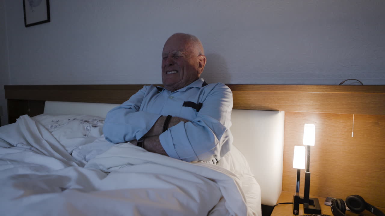 Elderly man in bed suffering from pain or sleeplessness