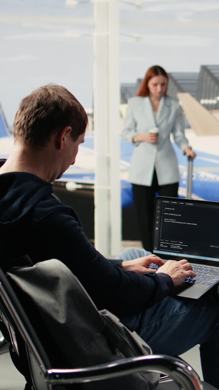 Vertical Video Digital nomad man programming on laptop in international airport