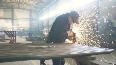 worker grinding metal in a factory