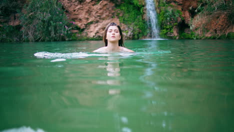 sexy lady swimming nature pool. seductive naked woman looking camera at lagoon