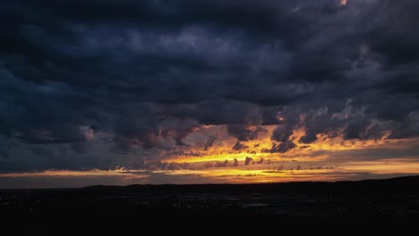 Toma-Aérea-Panorámica-De-Una-Puesta-De-Sol-Brillante-Pero-Misteriosa,-Tormenta-Rodando