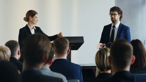 imprenditrice caucasica e uomo d'affari su un podio davanti all'uditorio e presentando un progetto a una conferenza