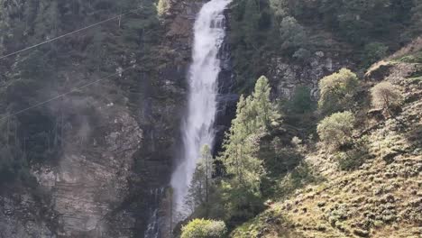 Kreisende-Luftaufnahme-Eines-Hohen-Wasserfalls-Zwischen-Den-Bergen