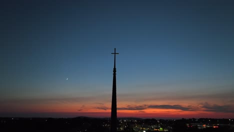 church spire silhouette against a sunset sky with a crescent moon