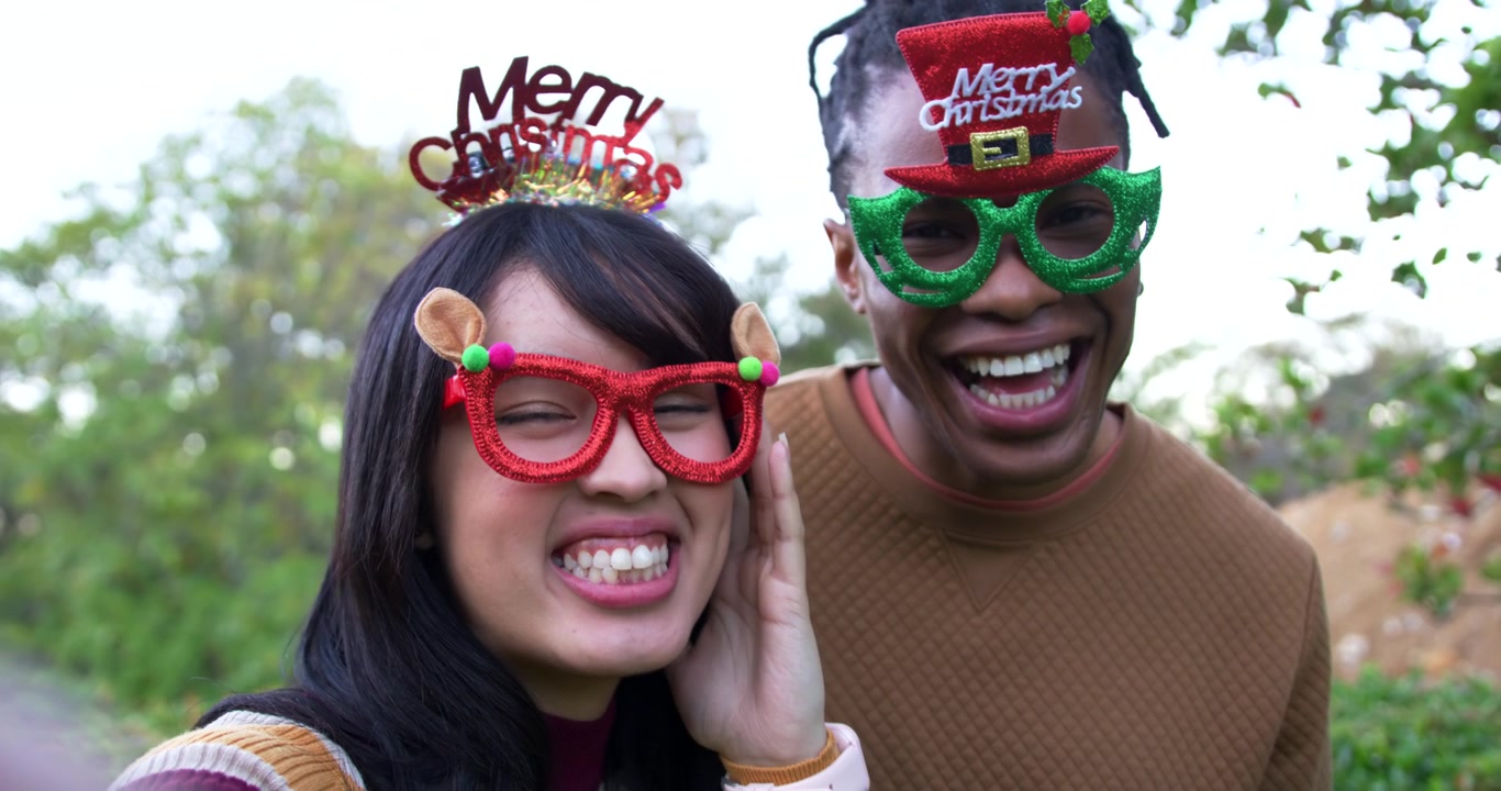 African American man and Asian woman couple posing, laughing, adjusting novelty glasses for camera