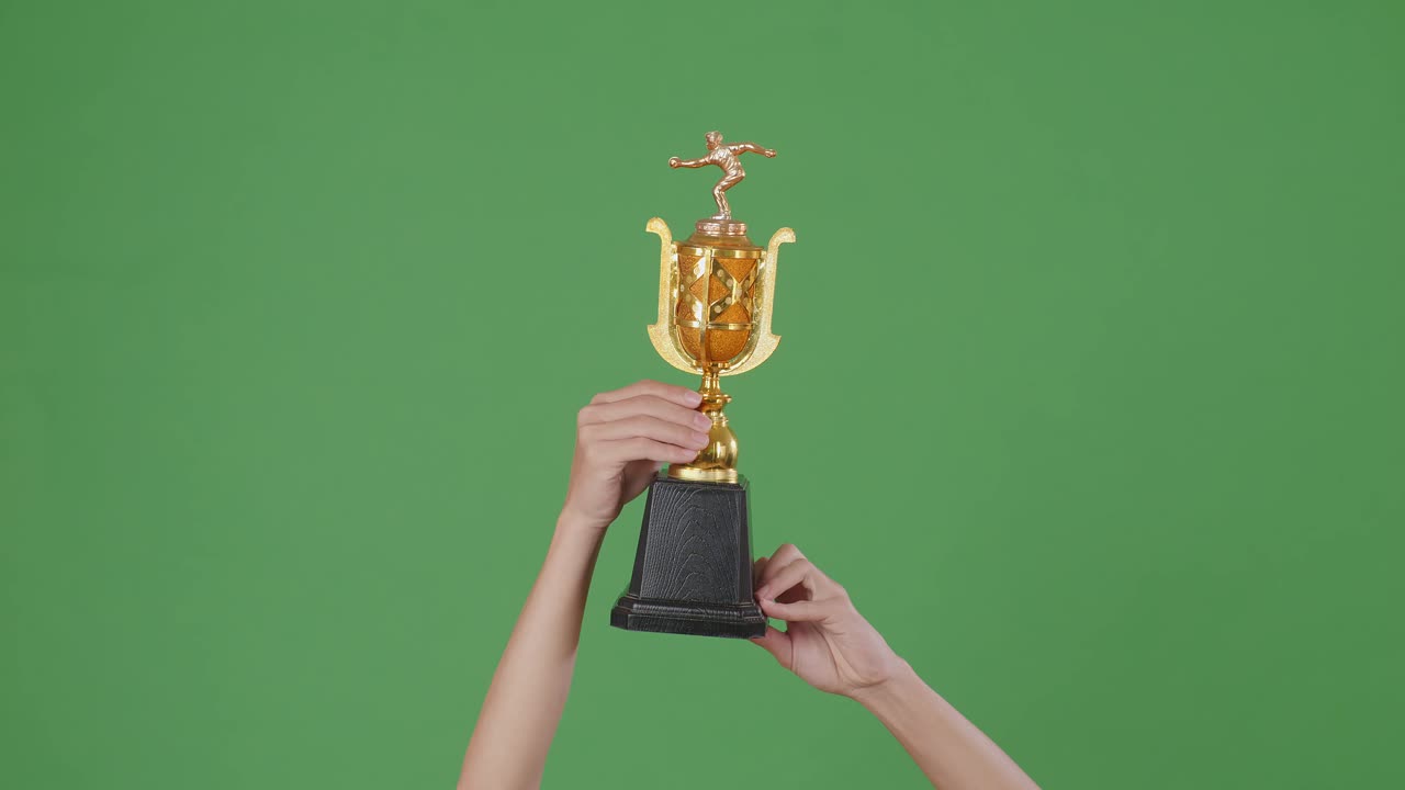 las manos levantadas de un hombre están sosteniendo un trofeo. fondo de pantalla verde