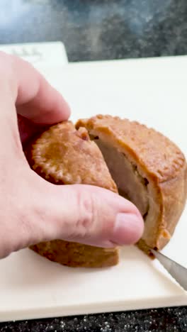vertical cutting a british pork pie on chopping board – close-up food preparation