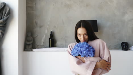 mujer en bata de baño sosteniendo flores