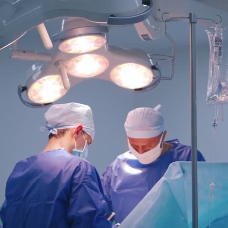 modern operating room with specialists. two surgeons with assistant perform a surgery under the bright lamp in the hospital.