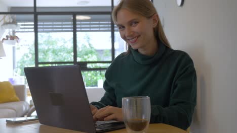 women using her laptop and smiling to the camera
