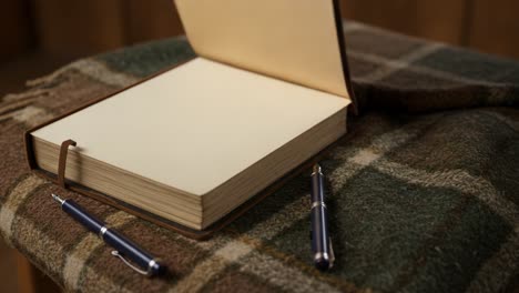 open notebook and pens on a plaid blanket