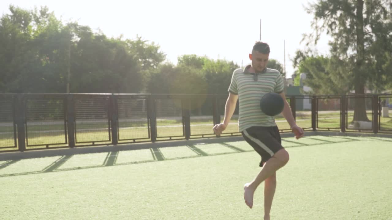 Adult man juggling soccer ball with his feet on artificial turf, showcasing his skills and passion for the sport