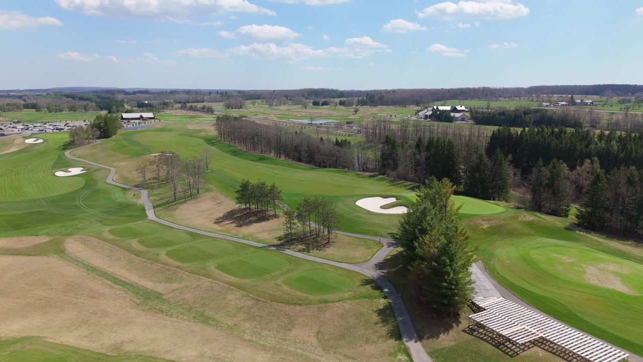 Ein Golfplatz mit Sandbunkern, grünen Fairways und gewundenen Wegen unter klarem Himmel. Geeignet für Golfwerbung oder Landschaftsaufnahmen