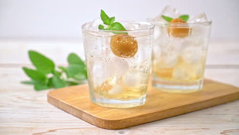 iced plum juice with soda and peppermint on wood table - refreshment drink