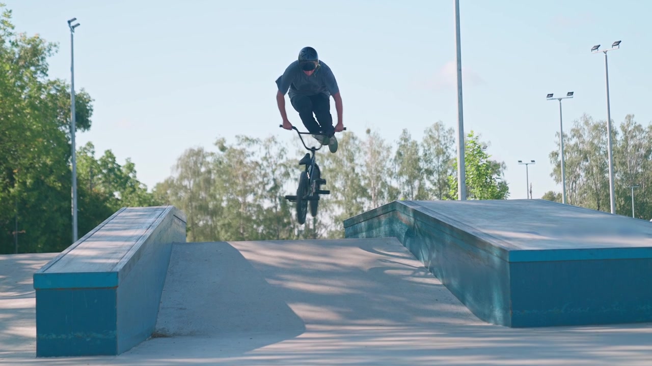 Ung mand hopper på BMX-cykel i skatepark