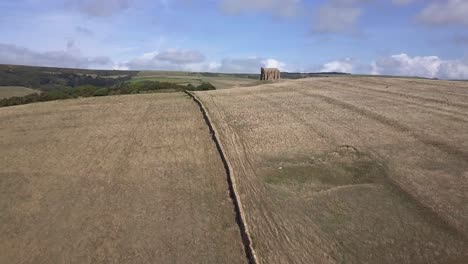 Aerial-tracking-forward-up-a-the-brow-of-a-hill-to-reveal-the-amazing-St-Catherine's-Chapel,-just-next-to-the-village-of-Abbotsbury