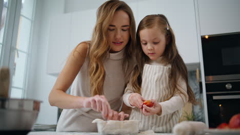 curious daughter decorating cake with mom kitchen closeup. woman teach kid bake