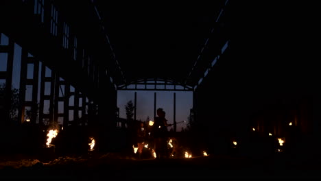 a group of people with fire and torches dancing at sunset in the hangar in slow motion. fire show.