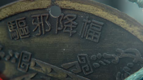 dreamy macro shot of a chinese ancient traditional lucky coin, asian new year decoration, golden shiny blur background, square hole, red strings, culture holyday, smooth pan right 4k video