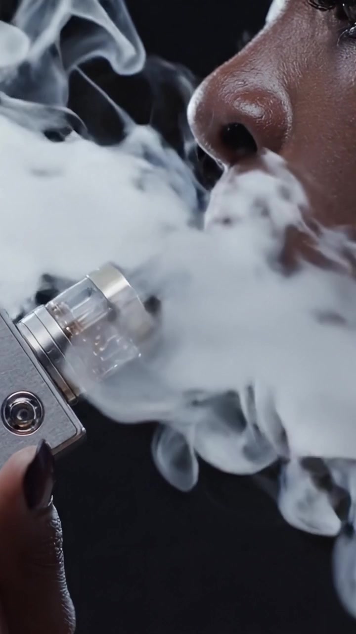 A Close-Up Exploration of Vaping: Distinct Facial Features and Vapor Clouds Captured in Two Stunning Frames of a Woman Enjoying a Smoke Experience