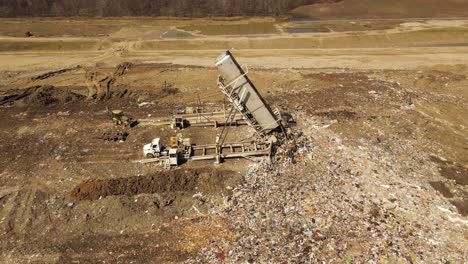 cargo truck unloading garbage trailer in landfill in michigan, aerial fly away view