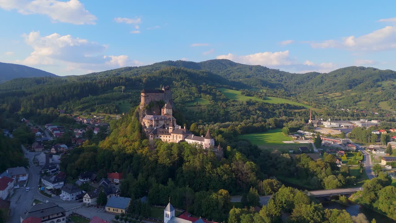 Luftaufnahme einer mittelalterlichen Burg auf einem Hügel, umgeben von einem Dorf