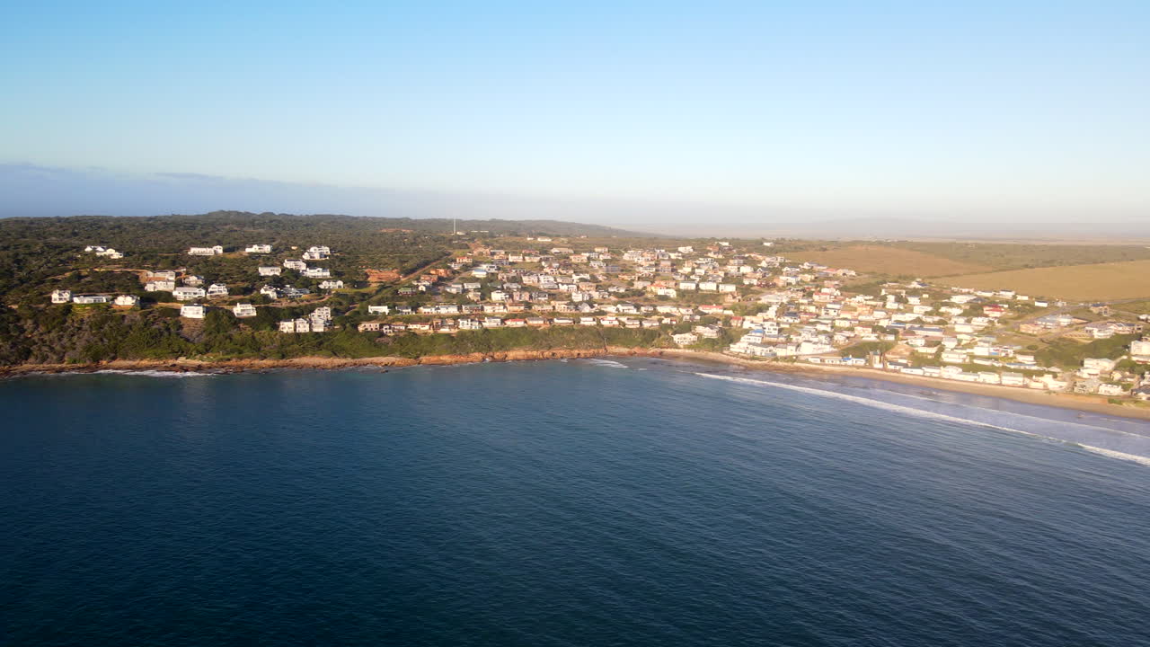Wide sunrise aerial pan shot over ocean of exclusive Vleesbaai near Mossel Bay