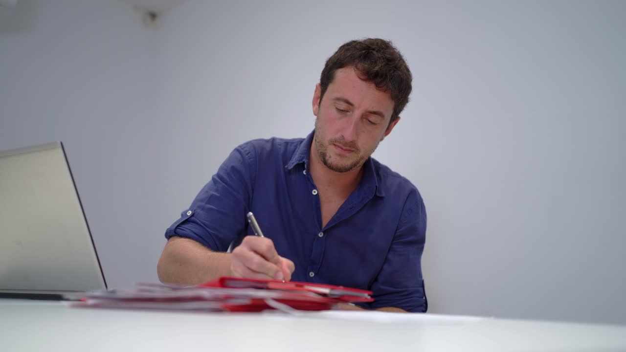 hombre serio escribiendo en un documento en una computadora portátil