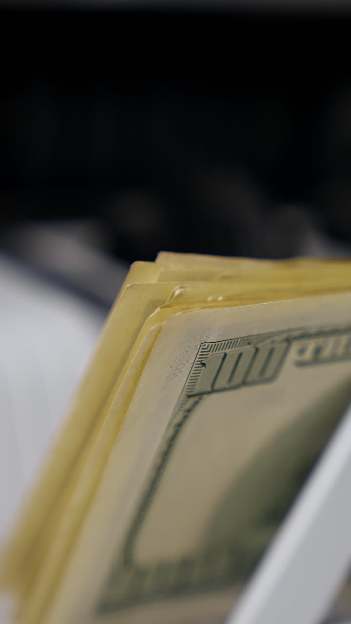 Cash money counting equipment. Currency counting machine counting dollar banknotes. Bank automatic equipment for counting paper money. Close-up. Vertical video