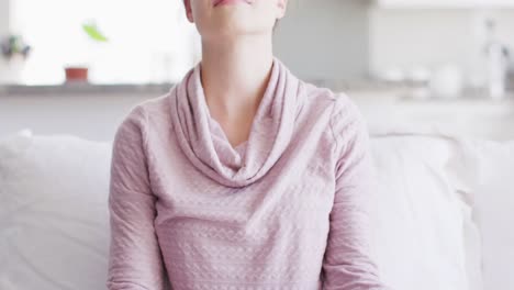 happy caucasian woman sitting on couch and meditating in living room