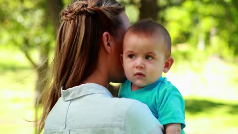 mother holding baby son in the park