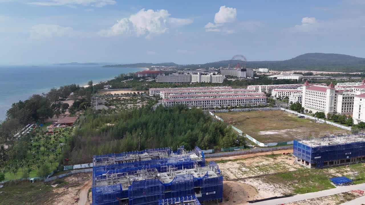 Aerial video of a construction site near to the beach. Island with a huge population. Blue lagoon. Drone footage during sunset near the beach.