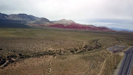 Aerial-of-Scenic-Roadway-in-the-foreground-flying-toward-the-red-rocks-of-Red-Rock-Canyon-in-Nevada