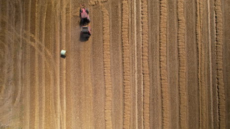 Vista-De-Pájaro-Sobre-El-Tractor-Que-Produce-Fardos-De-Heno-En-El-Campo---Disparo-De-Drones