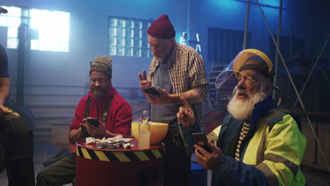 workers taking a break and using smartphones in an industrial setting