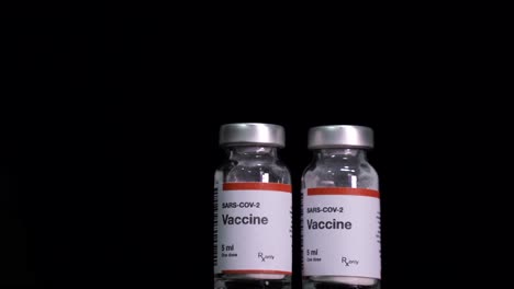 covid-19 vaccine into bottles placed on black background, coronavirus vaccination concept