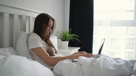 woman working on laptop in bed