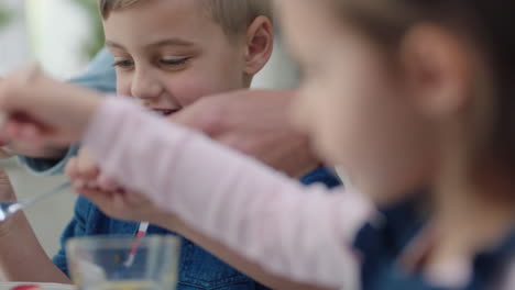 family having breakfast happy little boy eating pancakes with sister pouring delicious honey preparing homemade meal on weekend morning at home 4k footage