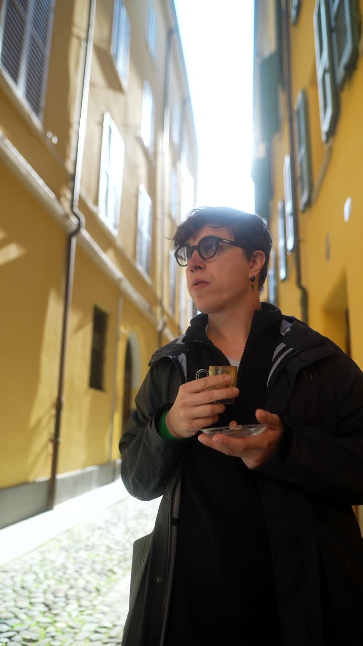 Person drinking coffee in a narrow city street