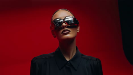 woman in futuristic sunglasses against red background