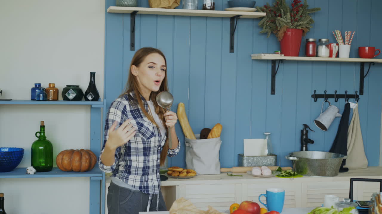 женщина поет и танцует на кухне