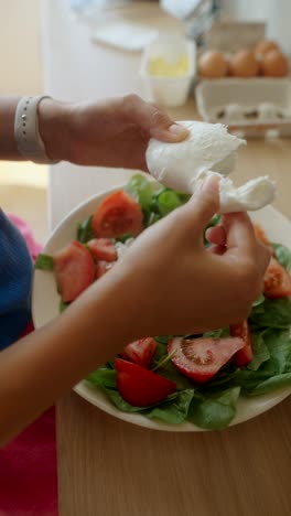 woman preparing a fresh tomato and spinach salad with mozzarella