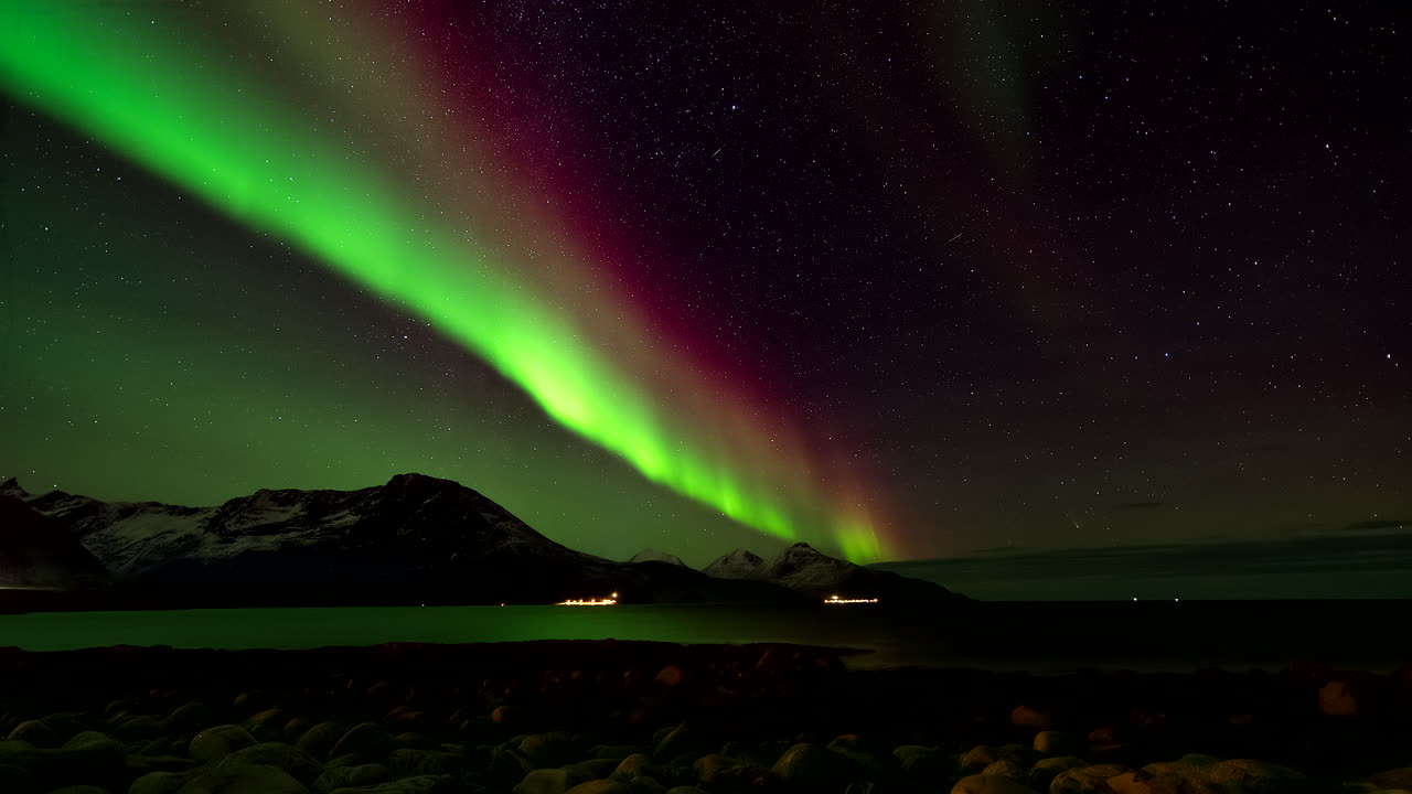 Timelapse notturno di suggestiva aurora boreale e stelle cadenti su un fiordo norvegese