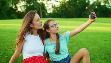 Girl-and-woman-taking-selfie-on-smartphone-in-park.-Family-using-mobile-phone