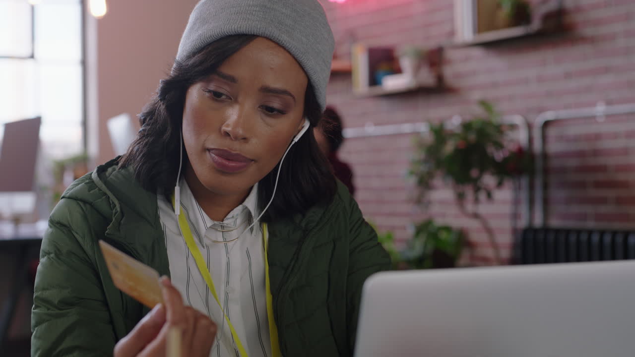 happy african american business woman shopping online banking using laptop computer spending money enjoying credit card purchase satisfaction smiling listening to music in modern startup office