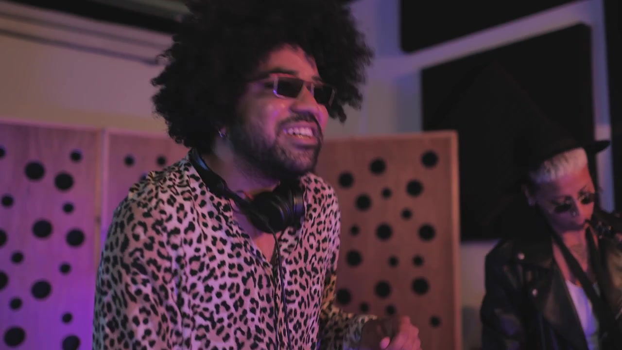 Uomo con camicia leopardata che fa il DJ in uno studio musicale colorato