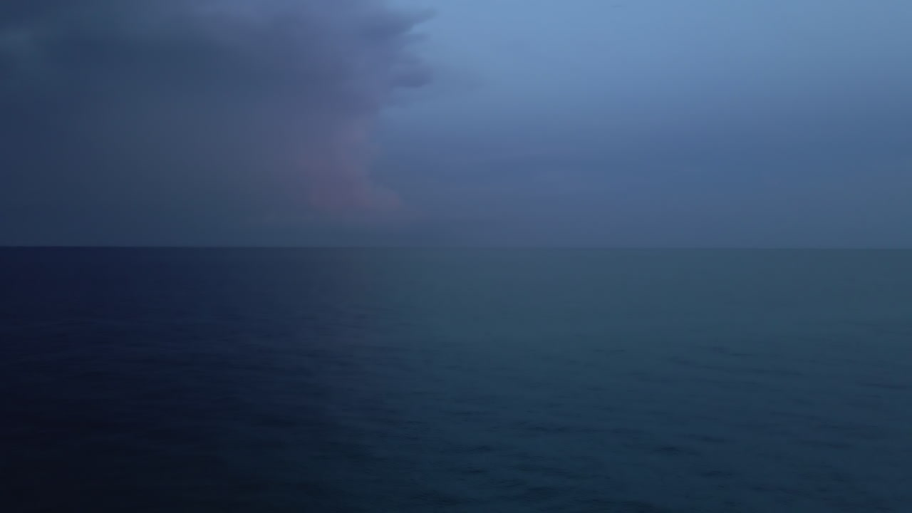 One lightning bolt strikes water in deep blue evening ocean scene