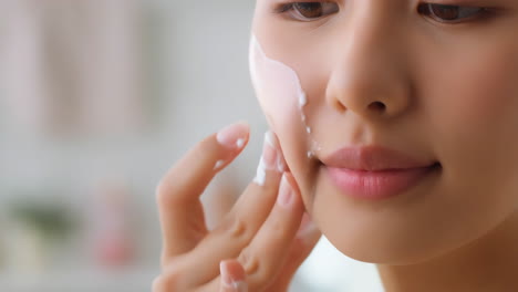woman applying skincare cream to her face