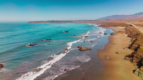 peaceful mesmerizing view of little waves slowly moving to the sandy shore on sunny day. scenery of morro bay, california, usa from top.